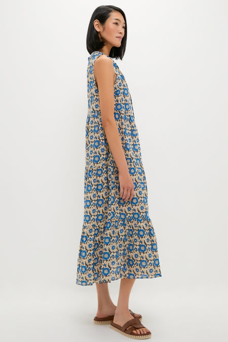 Woman in Cobalt Primose Salty Paloma Caftan, a classic, floral-print, sleeveless dress, styled with effortless, high-end flair, paired with fun brown woven-sole sandals.