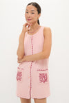 Woman in a classic, sleeveless Coral Embroidered Mini Bermuda Terrycloth Coverup with front buttons and scalloped trim, exuding effortless, high-end style with fun coral-branch accents.