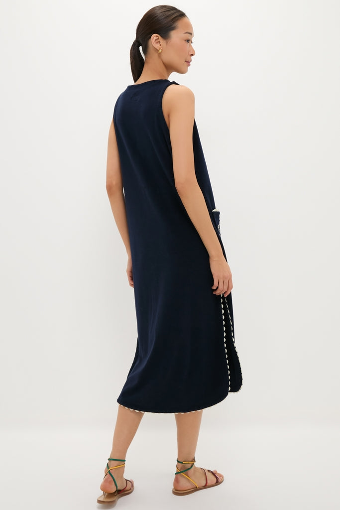 Model in Navy Embroidered Bermuda Terrycloth Caftan with white pom-pom trim, exuding effortless elegance, paired with colorful strappy sandals for a fun, high-end, classic look.