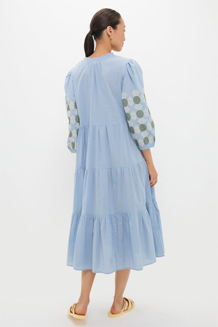 Woman wearing the Sky Geometric Embroidered Long Sleeve Salty Paloma Caftan, a classic, effortless, tiered midi dress with puff sleeves and high-end geometric embroidery, styled with gold sandals.