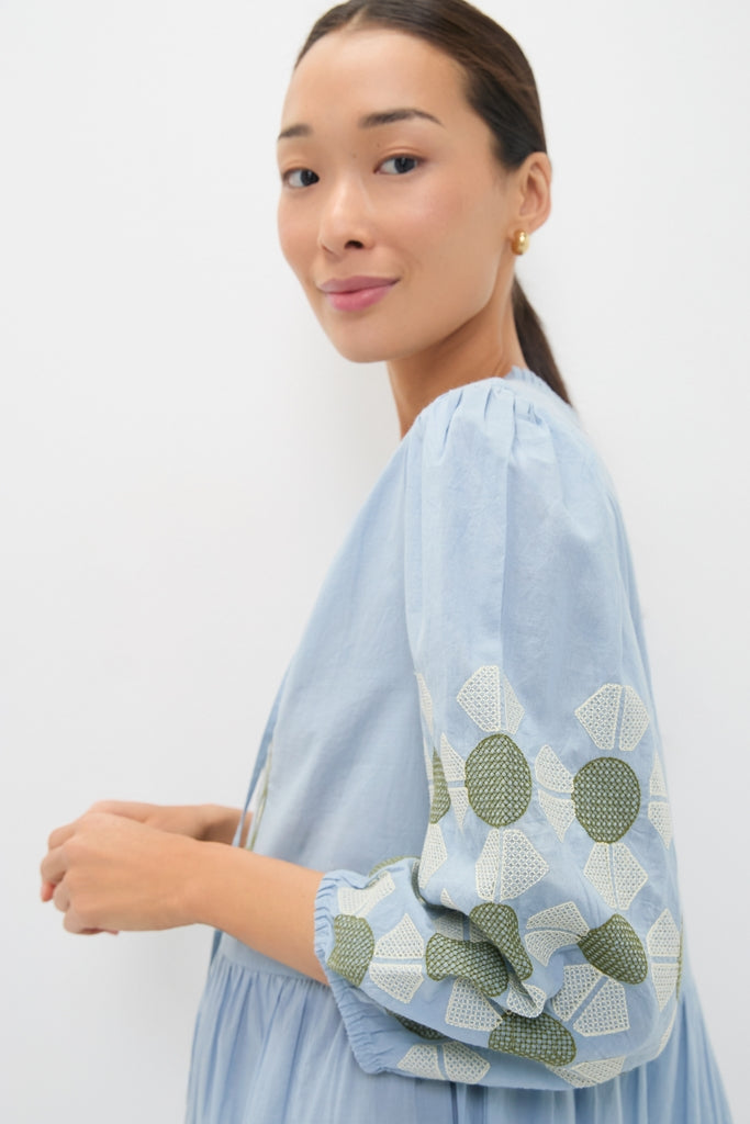 A young woman models the Sky Geometric Embroidered Long Sleeve Salty Paloma Caftan, showcasing its classic, effortless design with fun embroidered sleeves for a high-end look.