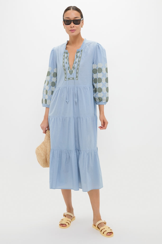 Woman wearing the Sky Geometric Embroidered Long Sleeve Salty Paloma Caftan, holding a straw tote, embodies a classic, effortless, and fun high-end style with geometric embroidery.
