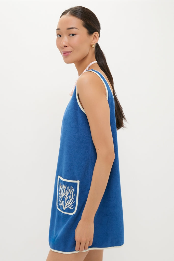 Young woman in profile wearing a classic, high-end Cobalt Embroidered Terrycloth Dress Coverup with white trim and coral motif, embodying effortless and fun style.