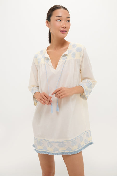 Woman wearing the Neblina Geometric Embroidered Bondi Coverup, a classic, effortless tunic dress with blue embroidery and tassels, embodying high-end, fun style against a light backdrop.