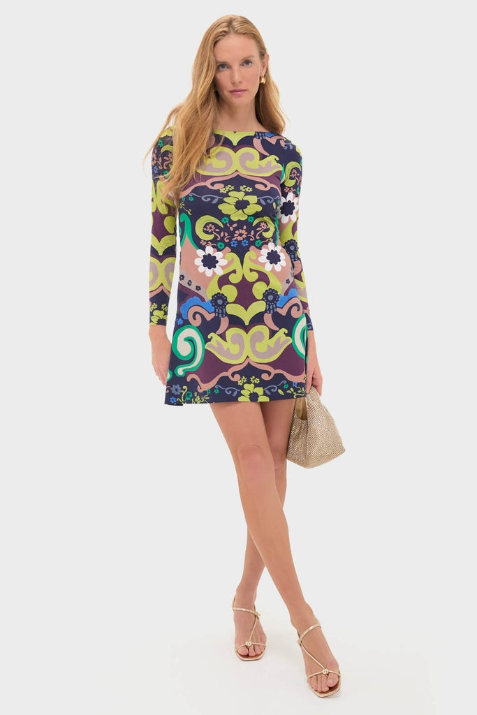 Model wearing the classic Papalote Rubi Dress, an effortless, high-end shift dress with a fun, multi-colored abstract pattern, paired with a metallic clutch and strappy sandals.