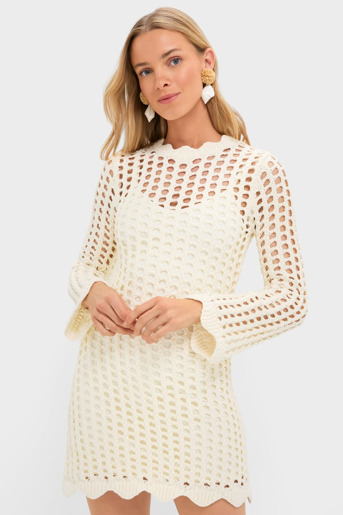 Ivory Knit Tamara Mini Dress: A classic, open-knit crochet design with scalloped edges, effortlessly styled with pom-pom earrings for a fun, high-end look.