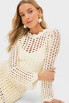 Young woman in an Ivory Knit Tamara Mini Dress with statement earrings, showcasing a classic, effortless style, perfect for a high-end, fun shopping experience.