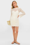 Ivory Knit Tamara Mini Dress: A classic crochet-style mini dress with scalloped edges, paired with a straw tote and lace-up sandals for an effortless, high-end resort look.