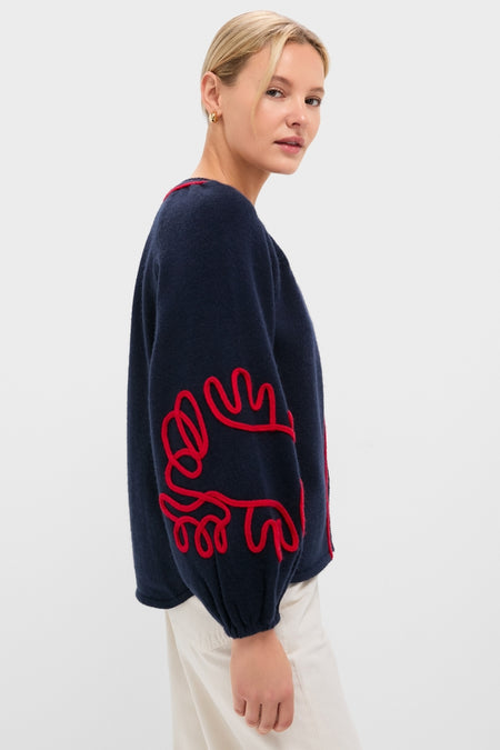 Profile view of a woman wearing the Navy & Red Soutache Stella Cardigan, featuring a classic, effortless design with fun red squiggly embellishments on a high-end, relaxed silhouette.