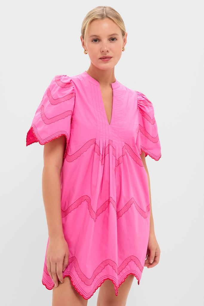 Model wearing the classic, effortless Hot Pink with Red Embroidery Weston Mini Dress, featuring puffed sleeves, scalloped trim, and a pleated front for a fun, high-end look.