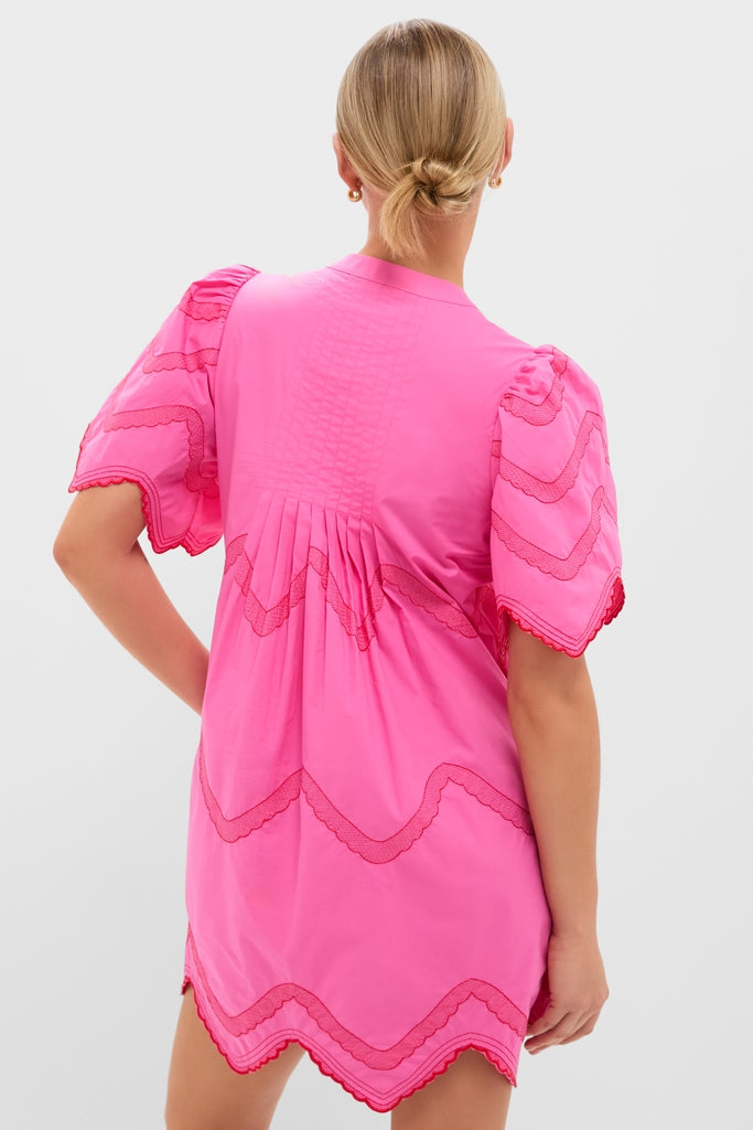 Woman wearing the Hot Pink with Red Embroidery Weston Mini Dress, featuring a classic, effortless babydoll silhouette with fun puff sleeves, scalloped edging, and high-end wave-pattern details.
