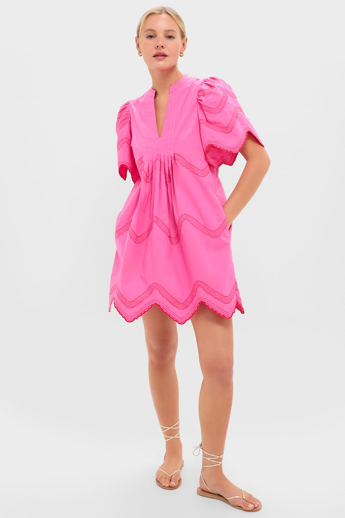 Woman in a classic, effortless Hot Pink with Red Embroidery Weston Mini Dress, featuring a V-neck, puffed sleeves, and scalloped hem, exuding a fun, high-end style.