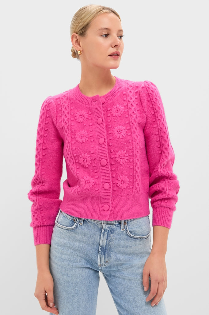 Person wearing the Hot Pink Embroidered Floral Frankie Cardigan, featuring bobble-and-floral cable-knit details, paired with high-waisted blue jeans for a classic, effortless, high-end look.