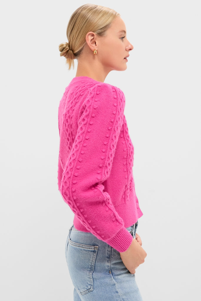Profile of a woman in a bright pink, cable-knit Hot Pink Embroidered Floral Frankie Cardigan, exuding a classic and effortless charm, paired with light-wash jeans.
