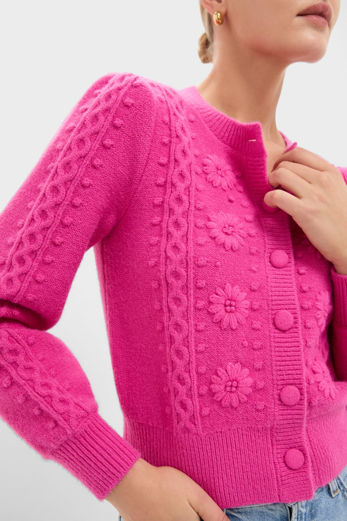 Hot Pink Embroidered Floral Frankie Cardigan with classic cable-knit and daisy motifs, effortlessly stylish with knitted buttons, paired with light-wash jeans for a fun, high-end look.