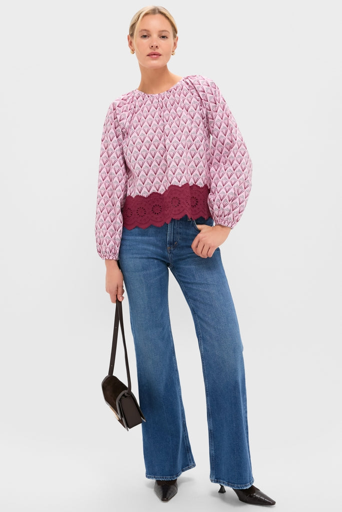 Model in Blush Trellis Floral Marika Blouse, showcasing a classic, effortless style with geometric print, scalloped hem, paired with flared jeans and black heels for a high-end, fun look.