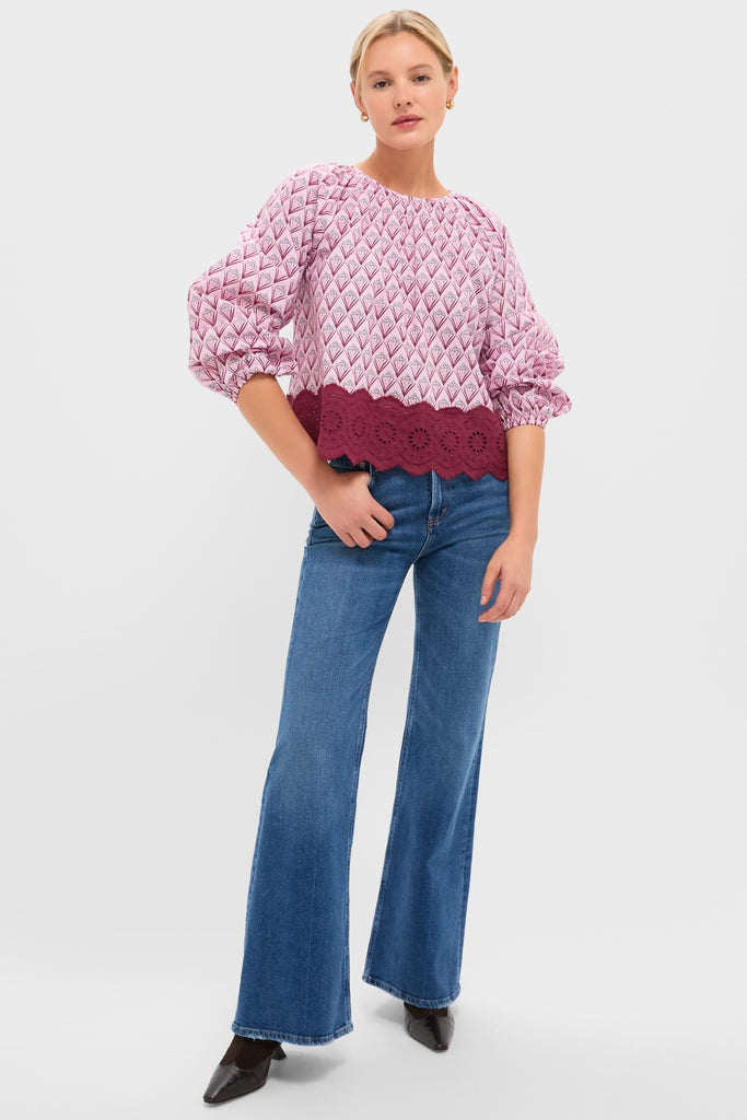 Woman modeling the classic Blush Trellis Floral Marika Blouse, featuring a relaxed fit and eyelet scalloped hem, paired effortlessly with high-waisted flared jeans.