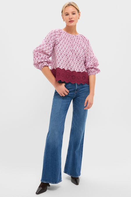 Woman modeling the classic Blush Trellis Floral Marika Blouse, featuring a relaxed fit and eyelet scalloped hem, paired effortlessly with high-waisted flared jeans.