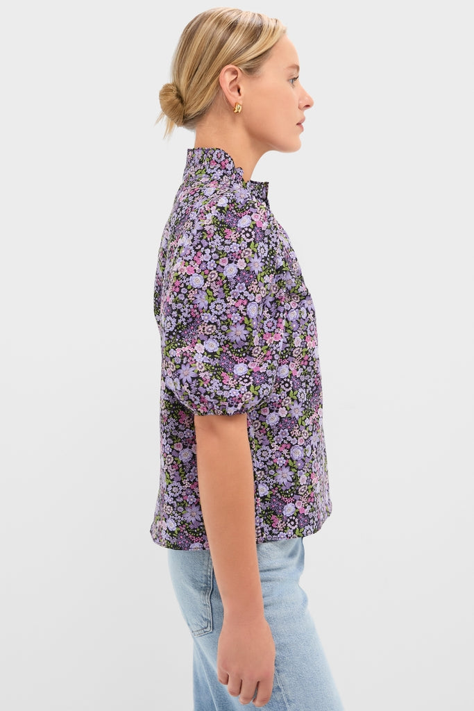 Model wearing the Shades of Purple Floral Florence Blouse, featuring a high ruffled collar and dense floral print, paired with light-wash jeans for a classic, effortless look.