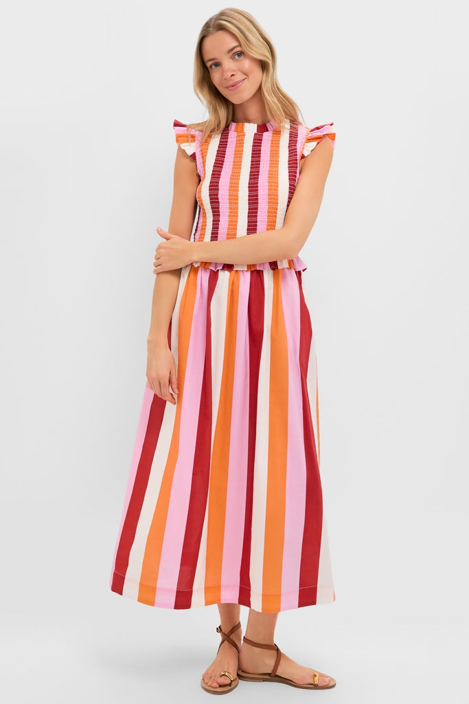 Woman models the classic Orange, Pink & Crimson Stripe Smocked Sully Dress, featuring a smocked bodice, ruffle cap sleeves, and an effortless A-line silhouette, paired with fun brown sandals.