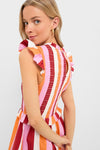 Woman in classic, effortless Orange, Pink & Crimson Stripe Smocked Sully Dress, featuring a smocked bodice, gathered skirt, and playful ruffle trims, embodying fun and high-end style.
