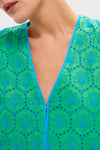 Seafoam Palm Eyelet Mini Arem Caftan showcases classic elegance with its effortless floral motif, bright blue embroidery, and fun eyelet details on a high-end green fabric.
