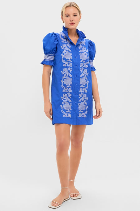 Young woman models the Royal Blue with White Embroidery Lou Lou Mini Dress, featuring a classic button-front design, puffed sleeves, and effortless floral detailing, paired with fun white sandals.