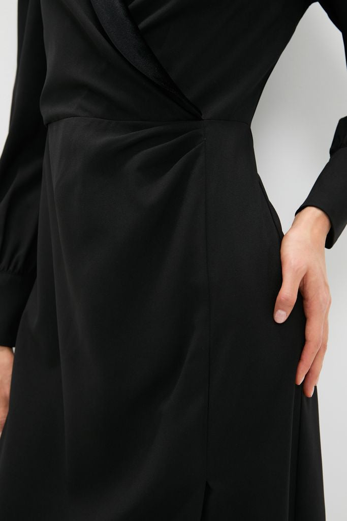 Black Long Sleeve Mariella Midi Dress with velvet trim, side gather, and blouson sleeves, showcasing classic, effortless style. Hand demonstrates side pocket, highlighting its high-end, fun design.
