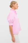 Woman models the Pink Candy Stripe Louisa Blouse, featuring a classic, high ruffled neckline and effortless puff sleeves, embodying Tuckernuck's fun and high-end style.