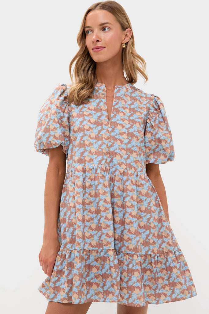Woman modeling the Brown & Powder Blue Floral Zip Front Ellie Mini Dress, featuring a classic, effortless tiered skirt and puff sleeves for a fun, high-end look.