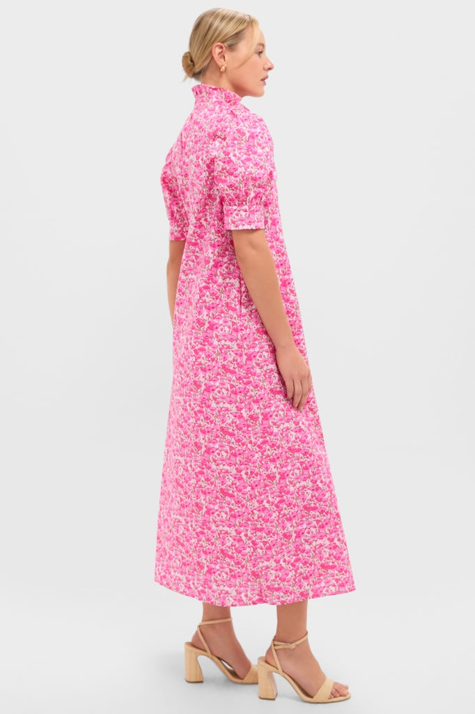 Woman in Pink Poppies Floral Louisa Maxi Dress with high neckline and A-line silhouette, exuding classic, effortless elegance, paired with nude strappy sandals.