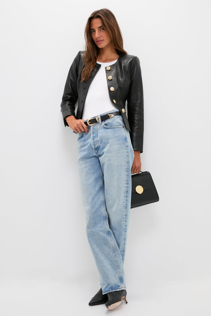 Woman models the classic Black Mariella Collarless Blazer with gold buttons, paired effortlessly with high-waisted jeans and a structured handbag for a fun, high-end look.