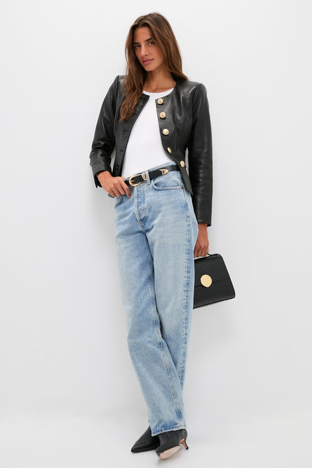 Woman models the classic Black Mariella Collarless Blazer with gold buttons, paired effortlessly with high-waisted jeans and a structured handbag for a fun, high-end look.
