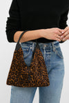 Leopard Medium Origami Shoulder Bag with a classic, effortless design, showcasing a bold leopard print and sculptural silhouette, held by a person in casual attire.