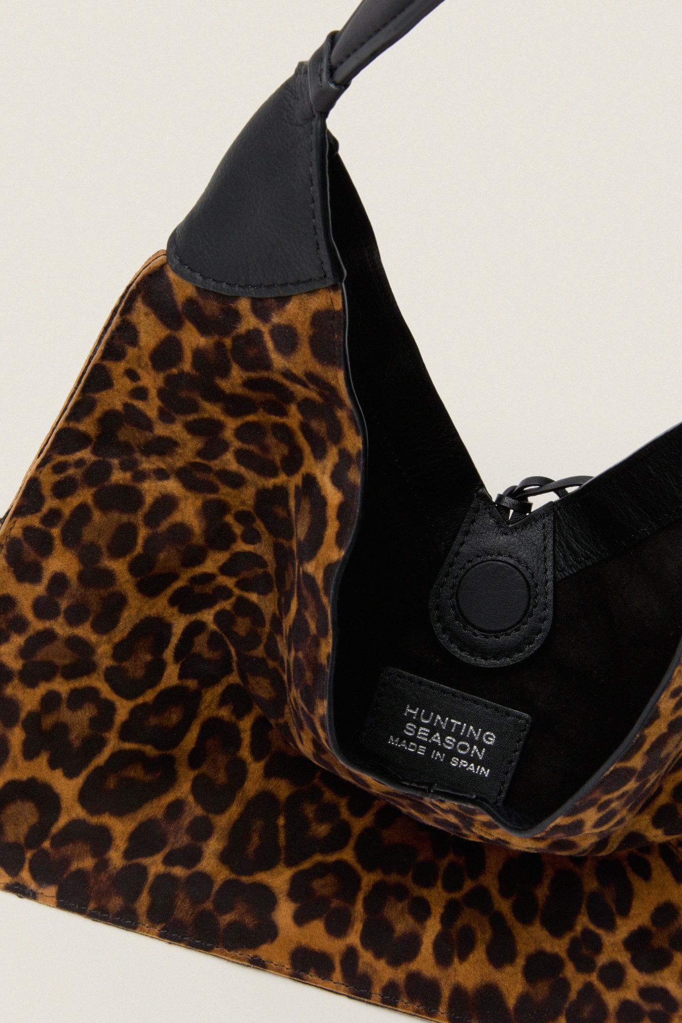 Leopard Medium Origami Shoulder Bag with a classic leopard-print, suede finish, black leather handle, and magnetic snap closure. Effortlessly fun and high-end, perfect for versatile styling.