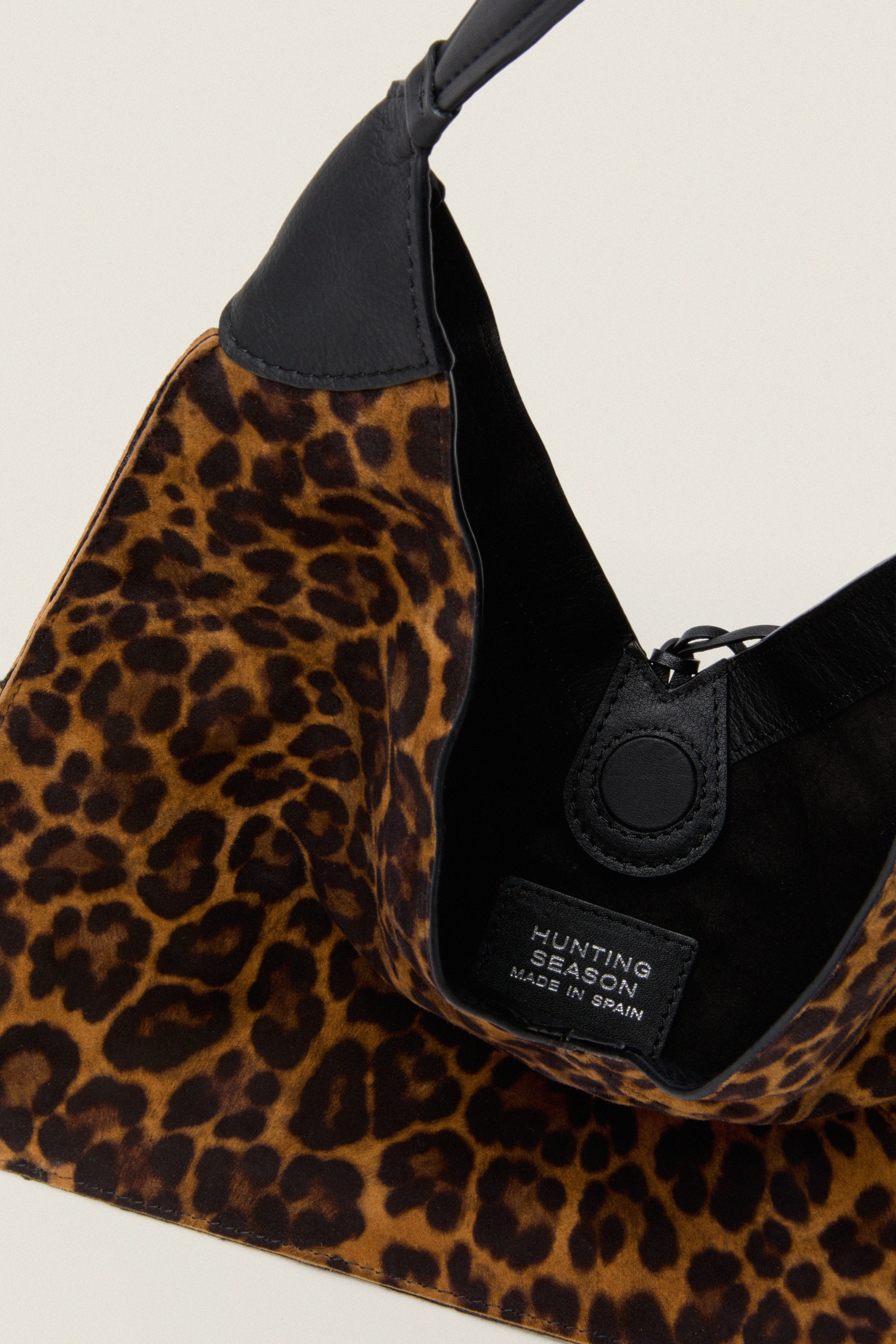 Leopard Medium Origami Shoulder Bag with a classic leopard-print, suede finish, black leather handle, and magnetic snap closure. Effortlessly fun and high-end, perfect for versatile styling.