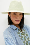 Young woman in a classic, effortlessly stylish Sage Novelty Packable Hat with intricate details, posing confidently in a fun, high-end fashion setting.