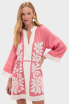 Woman models the Flora Pink Lumi Mini Dress, a classic, effortless tunic with floral embroidery, wide sleeves, and a fun, high-end feel, perfect for sunny days.