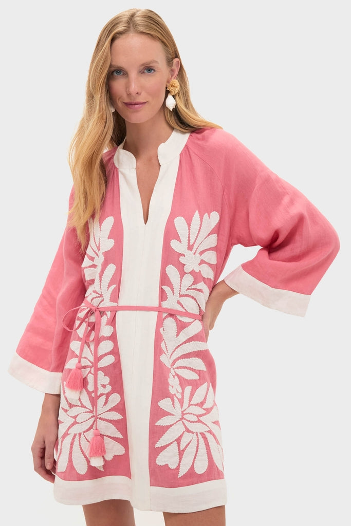 Woman models the Flora Pink Lumi Mini Dress, a classic, effortless tunic with floral embroidery, wide sleeves, and a fun, high-end feel, perfect for sunny days.