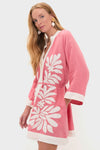 Woman models the Flora Pink Lumi Mini Dress, a classic kimono-style cover-up with white embroidered motifs, exuding effortless, high-end style with fun wide sleeves and a self-tie belt.