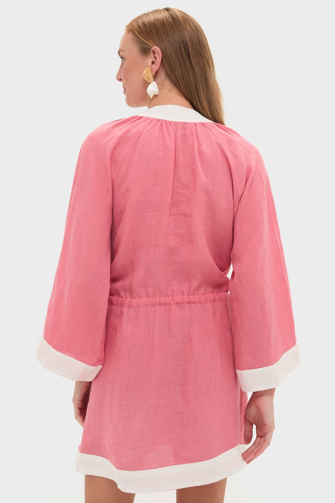 Woman wearing Flora Pink Lumi Mini Dress with white-trimmed hem and collar, shell earrings; a classic and effortless high-end look from Tuckernuck.