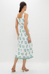 Woman in an Emerald Blossom Paloma Midi Dress, showcasing its classic, effortless style with a square neck and floral print. Paired with tan strappy heeled sandals.
