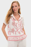 Woman wearing Hibiscus Bloom Pink Gabriella Shirt, a classic, effortless linen piece with pink floral embroidery and a relaxed camp-collar, embodying fun, high-end style.