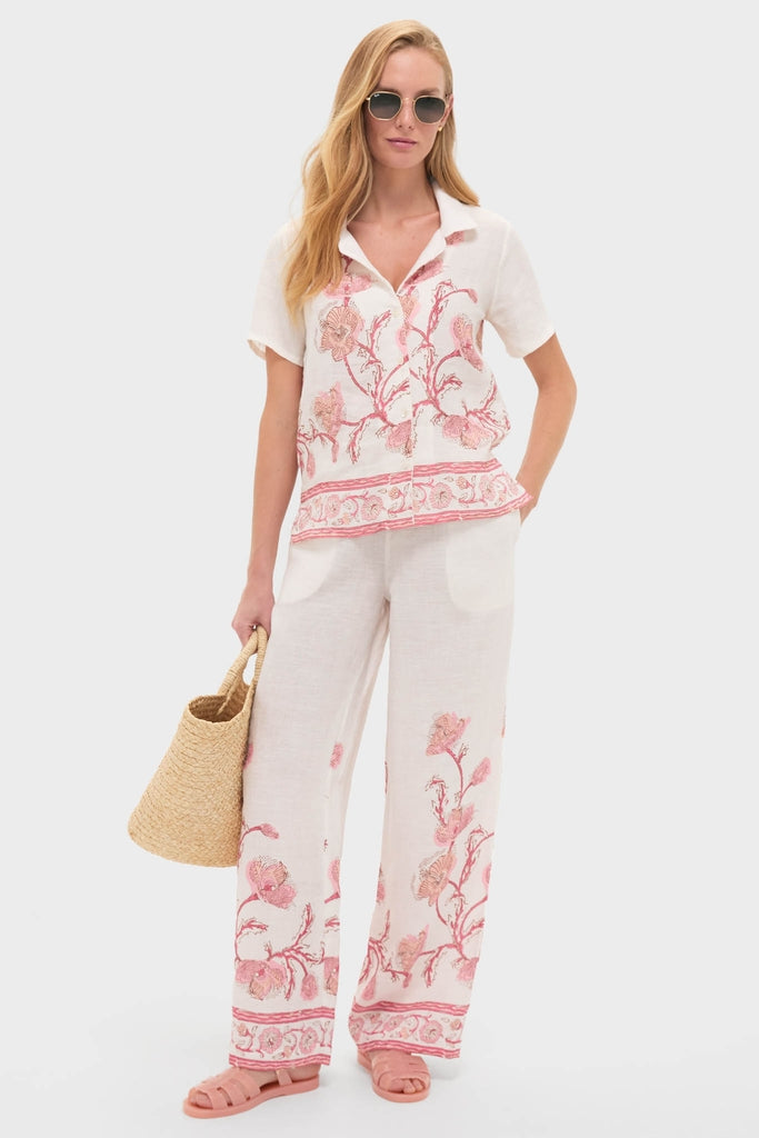 Woman models Hibiscus Bloom Pink Gabriella Shirt, a classic, effortless linen piece with floral detailing, paired with matching trousers for a fun, high-end ensemble.