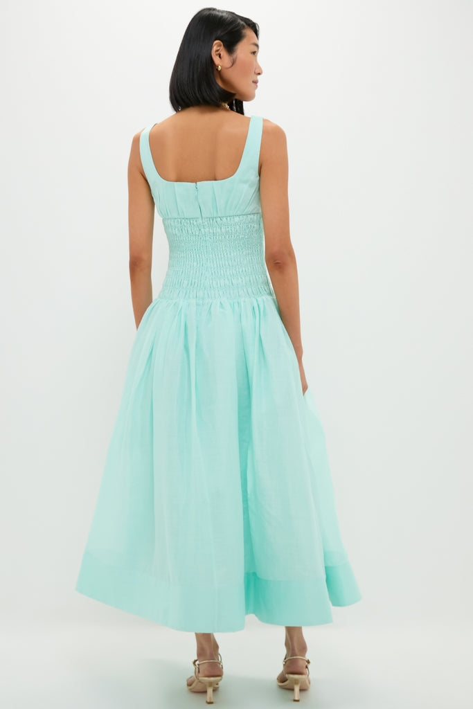 Woman in a classic mint green linen organza midi dress with a smocked bodice and gathered skirt, embodying effortless, high-end style with fun, elegant details.