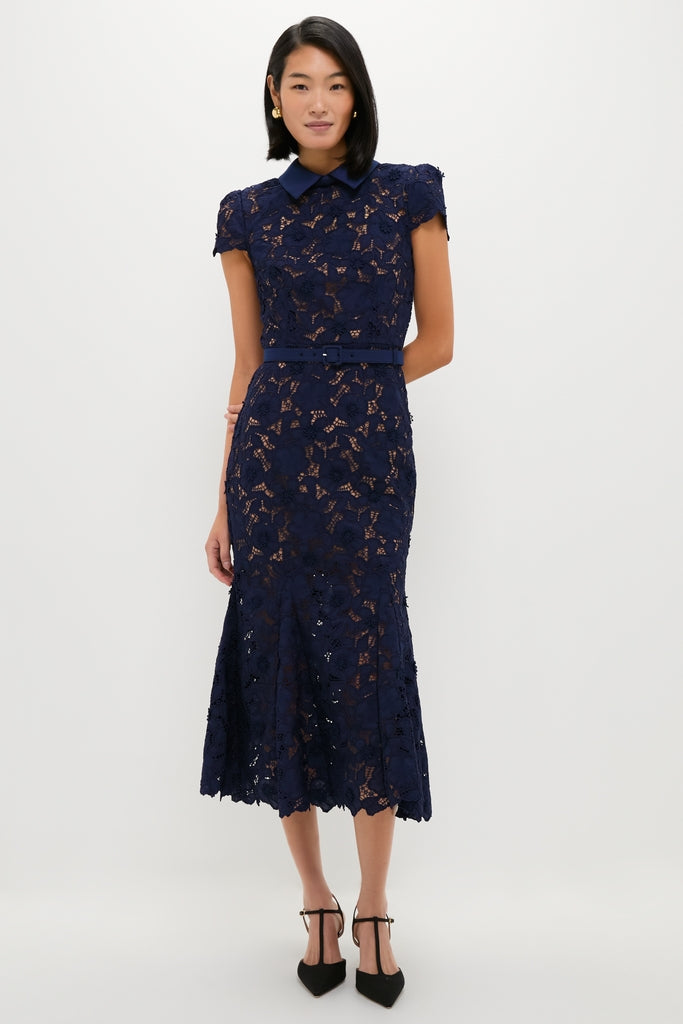 Navy Guipure Lace Midi Dress on model: classic design with pointed collar, capped sleeves, slim belt, floral lace overlay, and flared hem, paired with black T-strap heels. Effortless and high-end.