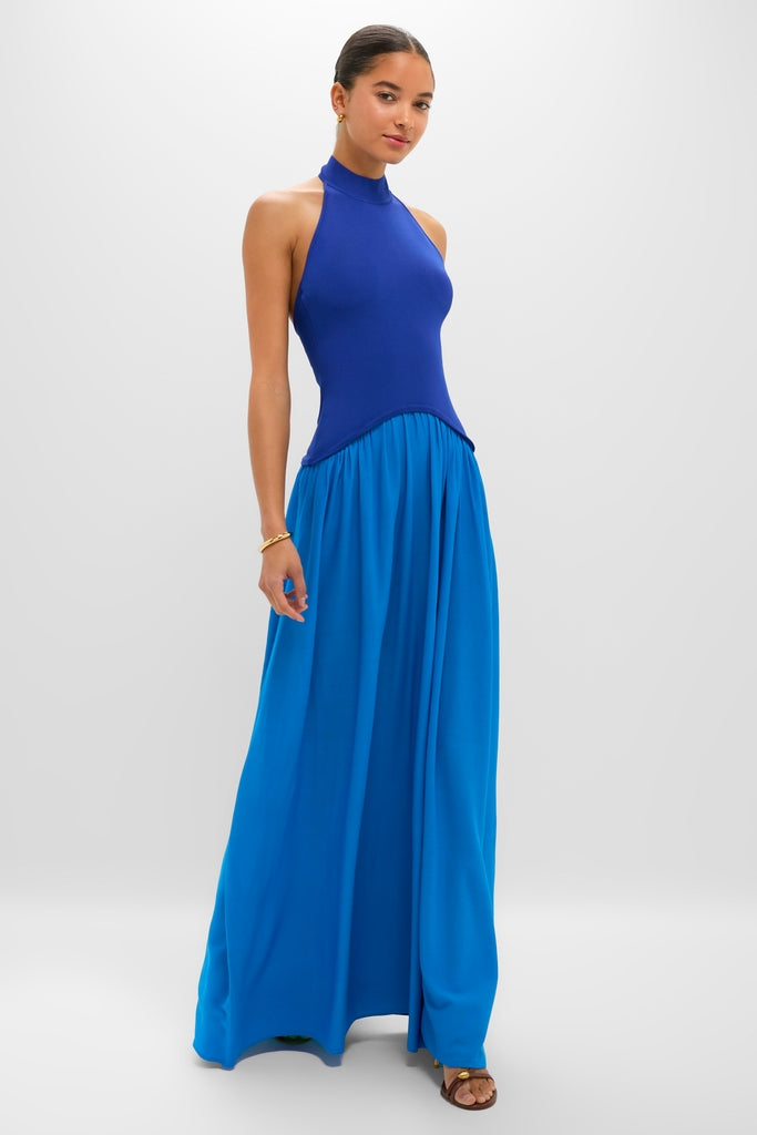 Young woman wearing the Cosmic Blue Soglio Halter Maxi Dress, featuring a classic fitted knit top and an effortless flowing skirt, embodying high-end, fun style.