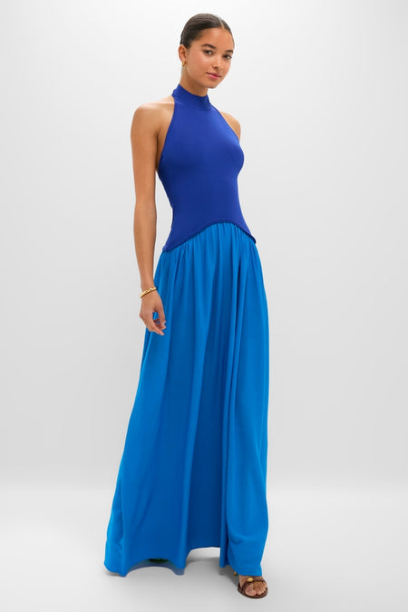 Young woman wearing the Cosmic Blue Soglio Halter Maxi Dress, featuring a classic fitted knit top and an effortless flowing skirt, embodying high-end, fun style.