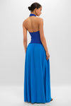 Woman modeling the classic, high-end Cosmic Blue Soglio Halter Maxi Dress with an effortless, two-tone design, combining a sleek knit top and flowing skirt, epitomizing fun and elegance.