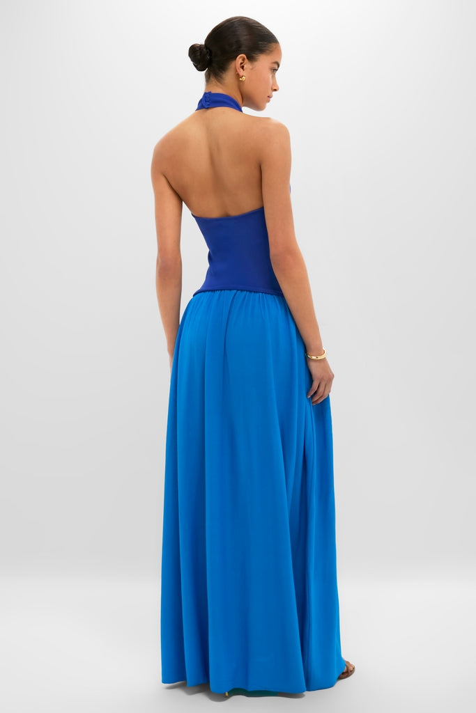 Woman modeling the classic, high-end Cosmic Blue Soglio Halter Maxi Dress with an effortless, two-tone design, combining a sleek knit top and flowing skirt, epitomizing fun and elegance.